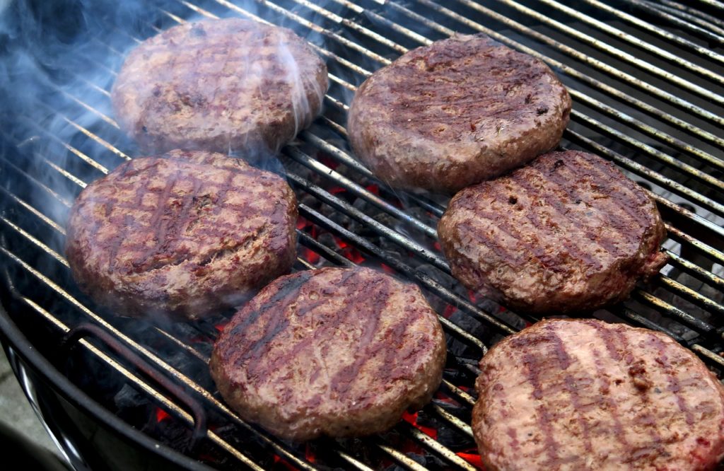 Des steaks hâchés sur un grill à charbon